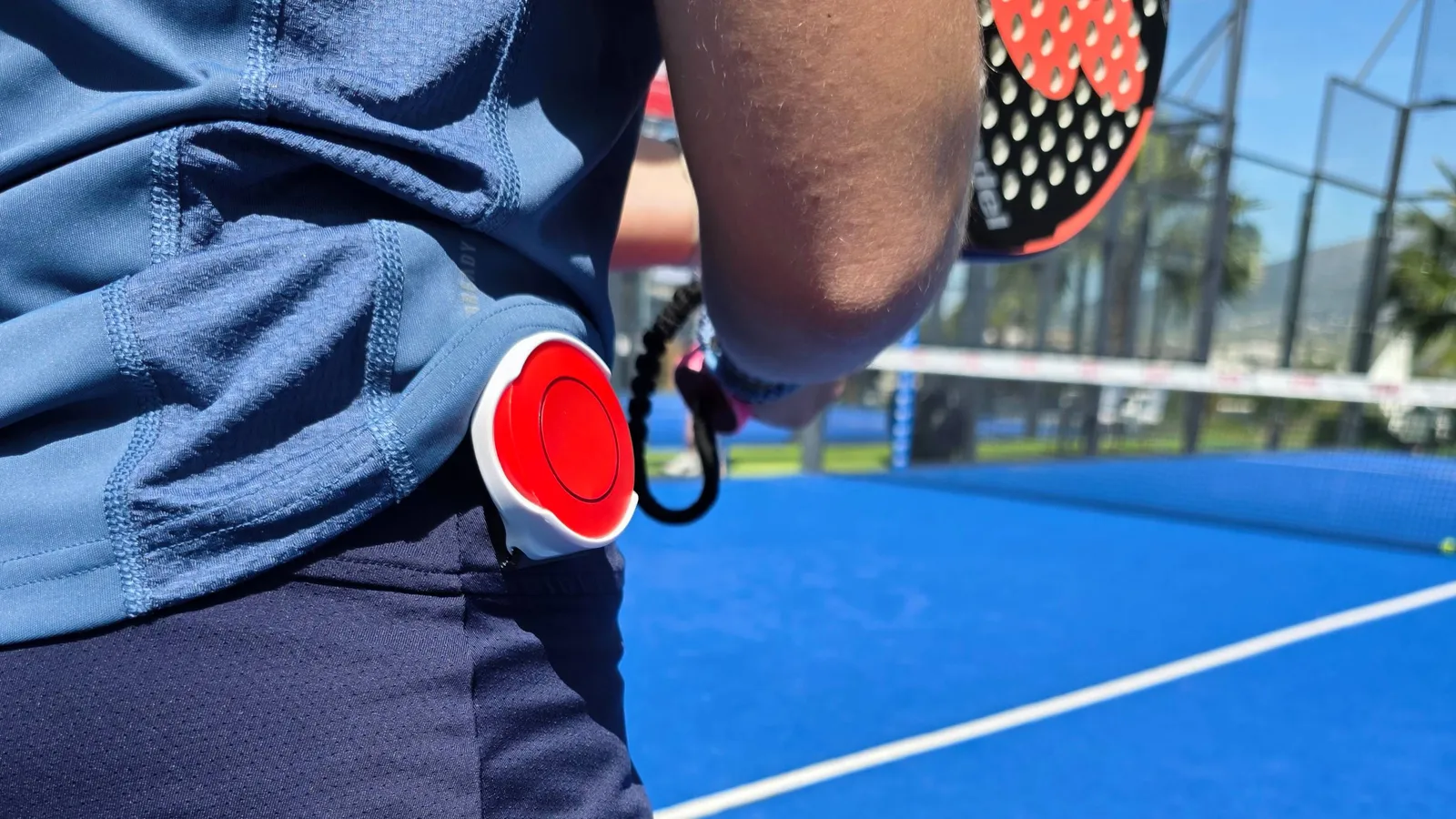 A padel player wearing the red LedsCount Go wearable RF remote.