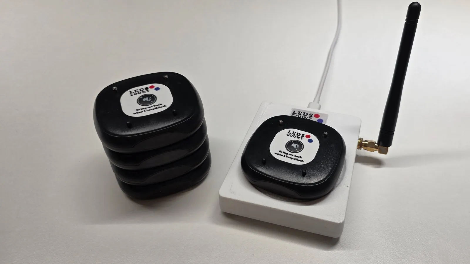 The LedsCount Pager Base Station next to a stack of pagers ready to issue.